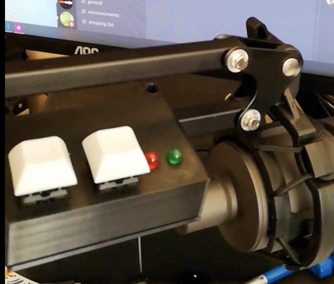 Image of device mounted on a microphone arm, it has two keyboard keys, and two LED's